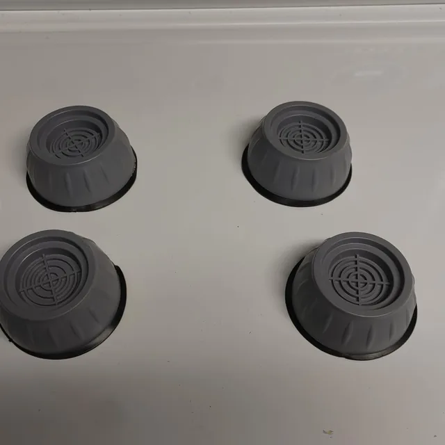 Cuatro soportes antivibración colocados sobre una lavadora blanca